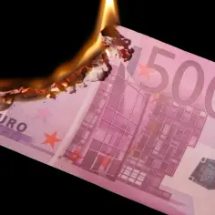 Płonący banknot 500 euro, dawna waluta Francji, symbolizuje straty finansowe.