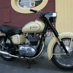 Klasyczny motocykl Junak, przypominający wyglądem chińskie motocykle 125, z kremowym lakierem i czarnymi detalami.
