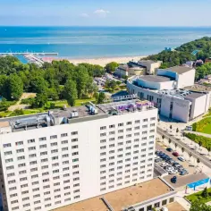 Widok z lotu ptaka na hotel Mercure Gdynia z widokiem na morze, plażę i marinę.