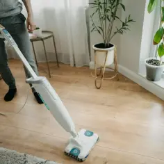 Osoba czyści panele podłogowe mopem parowym. Czy mop parowy niszczy panele? Zobacz, jak skutecznie i bezpiecznie pozbyć się zabrudzeń.