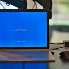 Laptop z niebieskim ekranem Windows, na którym trwa aktualizacja. Proces "windows modules installer worker" jest w toku, postęp 27%.
