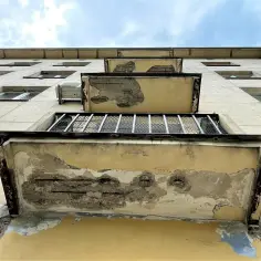Zniszczone balkony kamienicy, z których odpada tynk, odsłaniając zbrojenie. Potrzebny jest specjalny środek, inhibitor, by zatrzymać dalszą korozję.