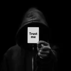 Postać w kapturze trzyma kartkę z napisem "Trust me". Może to symbolizować oszustwo, jak w art. 286 kk.