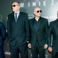 Obsada filmu "Psy: W imię zasad" na premierze: czterech mężczyzn w garniturach i okularach przeciwsłonecznych.