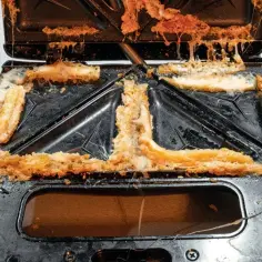 Wnętrze tostera mocno zabrudzone okruchami i przypalonym serem. Czas na czyszczenie!