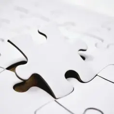 Biała, pojedyncza kostka puzzli leży na tle innych, tworząc paradoks co to znaczy, gdy brakuje jednego elementu?