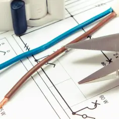 Niebieski czy brązowy kabel to plus? Schemat elektryczny, przewody i nożyczki sugerują, że to kluczowe pytanie przy instalacji.