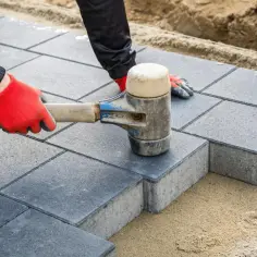 Układanie kostki brukowej. Różne rodzaje kostki brukowej tworzą estetyczną nawierzchnię, układaną za pomocą gumowego młotka.