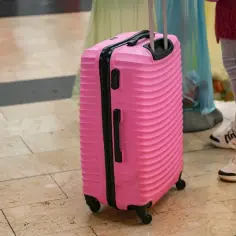 Różowa walizka na kółkach na lotnisku.