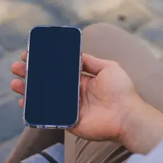 Mężczyzna trzyma iPhone'a. Dowiedz się, jak wyłączyć iPhone bez dotykania ekranu, naciskając przyciski.