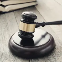 Młotek sędziowski i otwarte księgi na drewnianym stole. Symbol sprawiedliwości i licytacja elektroniczna.