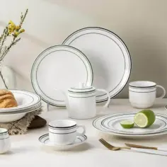 Elegancka zastawa stołowa z porcelany i kamionki, z subtelnymi czarnymi i zielonymi paskami, idealna na śniadanie.