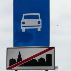 Znak drogowy ekspresowy z symbolem samochodu i znak końca drogi ekspresowej z sylwetką miasta.