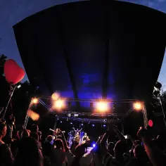 Koncert w amfiteatrze w Kołobrzegu. Tłum bawi się pod sceną, na której gra zespół. W powietrzu unosi się czerwone serce.