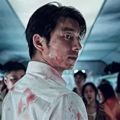 Mężczyzna w zakrwawionej koszuli, otoczony przez ludzi w wagonie. Scena z filmu o zombie, pełna napięcia i grozy.