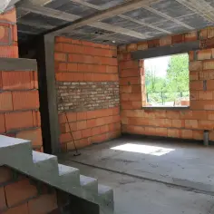 Trwa przekształcenie budynku gospodarczego na mieszkalny. Widoczne schody, ściany z cegły i betonowy strop.