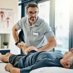 Fizjoterapeuta wykonuje ćwiczenia z pacjentem, co jest kluczowe, gdy zastanawiamy się, co jest potrzebne do zasiłku rehabilitacyjnego.