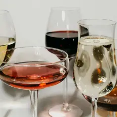 Jak dobrać tanie dobre wino w supermarkecie do 30 złotych? Kieliszki z białym, różowym, czerwonym winem i szampanem.