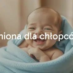 Uśmiechnięty noworodek otulony kocykiem. Tekst "Imiona dla chłopców" sugeruje poszukiwanie ciekawych imion męskich dla maluszka.