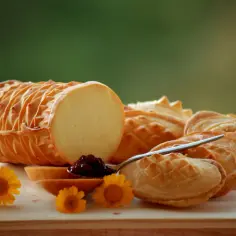 Oscypek, mleko, dżem i kwiaty na desce.