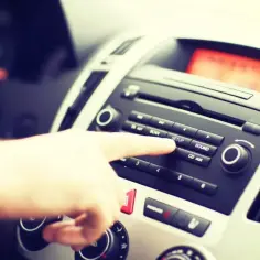 Palec naciska przycisk "SETUP" na radiu samochodowym. Dowiedz się, jak podłączyć radio samochodowe żeby trzymało pamięć.