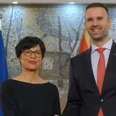 Kobieta i mężczyzna stoją obok flagi UE i Czarnogóry. Czy Czarnogóra jest w Unii? To pytanie nabiera znaczenia w kontekście ich spotkania.