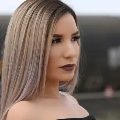 Kobieta z blond włosami, które wyglądają jak po zabiegu nanoplastia, z ciemną szminką na ustach.
