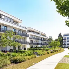 Nowoczesne apartamentowce z balkonami i zielenią. Dbałość o detale, jak ścieżki i stojaki na rowery, świadczy o dobrym zarządcy budynku.