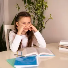 Dziewczynka zamyślona nad książką, być może zmaga się z dysleksją rozwojową.