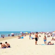 Tłum ludzi na piaszczystej plaży, szukających odpowiedzi na pytanie: gdzie najbliżej nad morze z Warszawy.