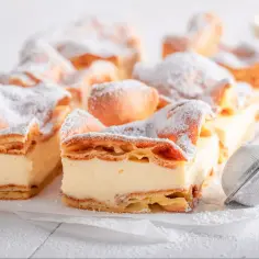 Pyszna karpatka z kremem, posypana cukrem pudrem. Idealna na deser, gdy masz ochotę na coś słodkiego.