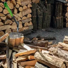Stos drewna opałowego, siekiera wbita w pień. Wartość drewna opałowego za m3 zależy od gatunku i wilgotności.