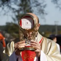 Ksiądz trzyma monstrancję z hostią, na której widoczna jest plamka.