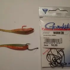 Dwie gumowe przynęty wędkarskie typu worm i opakowanie haczyków Gamakatsu.