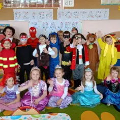 Dzieci w strojach postaci z bajek pozują do zdjęcia w przedszkolu.