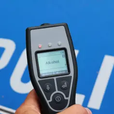 Alkomat w ręku, na tle napisu "POLICJA". Czyżby kolejny rekord promili w Polsce?