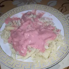 Porcja makaronu fusilli polana kremowym, różowym sosem z kawałkami owoców. Pyszny makaron na słodko.