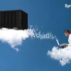 Synology Drive: mężczyzna na chmurze pracuje na laptopie, z którego wylatują litery, kierując się do serwera Synology na innej chmurze.