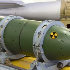 Zielona bomba nuklearna z symbolem promieniowania, gotowa do użycia. W tle widać inną, większą bombę.