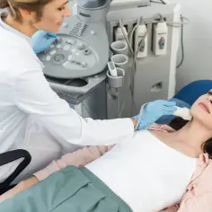 Lekarka wykonuje badanie usg szyi pacjentce leżącej na kozetce.