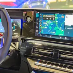 Wnętrze samochodu z ekranem nawigacji i mapą. Widoczna kierownica i przyciski. To wszystko działa dzięki android auto najnowsza wersja.