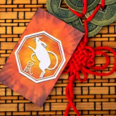 Chiński znak zodiaku - mysz, symbol roku 2008, na tle bambusowej maty z monetami i czerwonym węzłem.