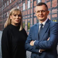 Dwoje prawników, kobieta i mężczyzna, stoją przed ceglanym budynkiem.