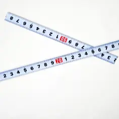 Dwie miarki zwinięte na krzyż, pokazujące liczby od 1 do 30. Pomocne przy pytaniu, jak zmierzyć rozmiar felgi.