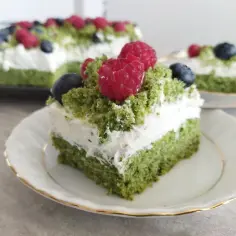 Zielony, puszysty **ciasto leśny mech na dużą blachę z serkiem mascarpone**, udekorowane malinami i borówkami.