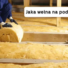 Ocieplanie poddasza wełną mineralną. Ręce w rękawiczkach układają rolkę izolacji.