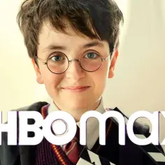 Młody aktor w okularach i szacie Hogwartu, przypominający młodego Harry'ego Pottera, z klapsem filmowym. To część obsady Harry Potter na HBO Max.