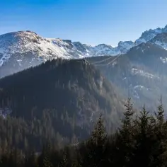 Zimowe Tatry, ośnieżone szczyty i gęste lasy. Kolejka linowa wznosi się ku górze, potwierdzając, czy w Tatrach opady są znacznie większe niż na nizinach.
