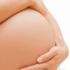 Dłoń kobiety obejmuje ciążowy brzuch. Badanie HBs antygen w ciąży jest ważne dla zdrowia matki i dziecka.