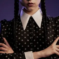 Aktorka Wednesday Addams w czarnej sukience z białym kołnierzykiem i warkoczami.